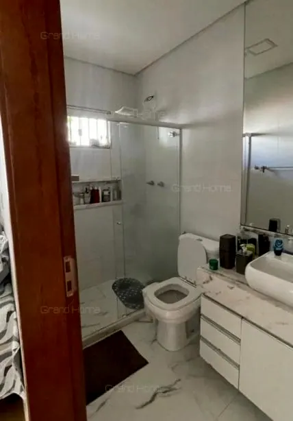 Banheiro com box de vidro e bancada branca