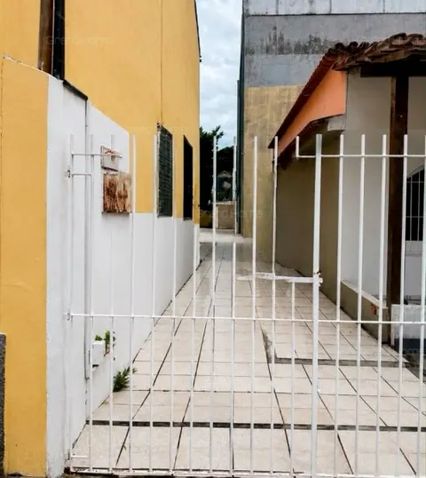Corredor lateral com piso cerâmico e portão branco