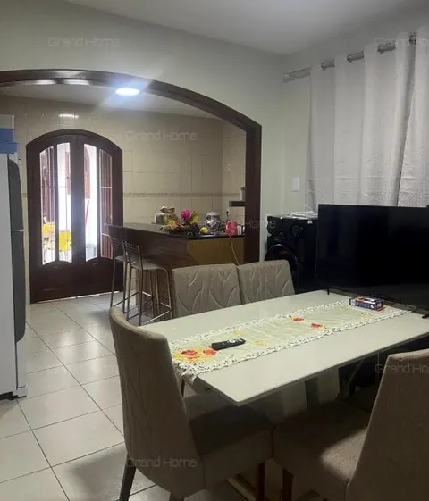 Sala de jantar com mesa e cadeiras, e passagem em arco ao fundo