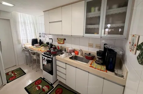 Cozinha com armários brancos e bancada de refeições