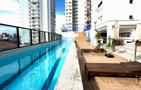 Piscina do condomínio com deck e espreguiçadeiras de madeira